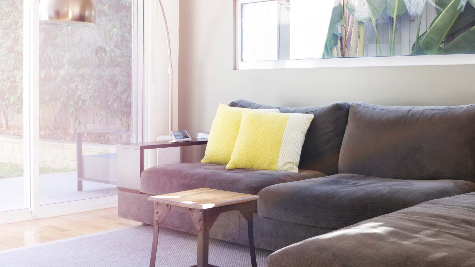 crestron touch panel in living room with grey couch and yellow pillows