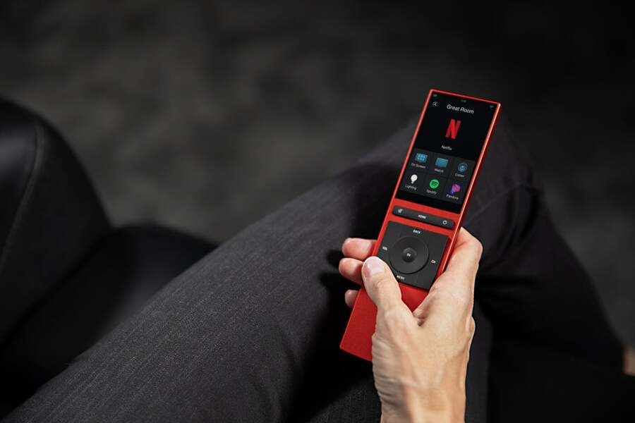 A person is holding the Neeo Control4 remote.