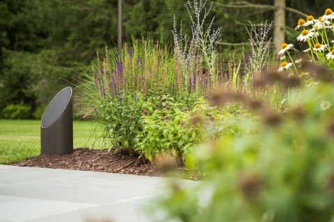 The Coastal Source Bollard speaker in a flowerbed.