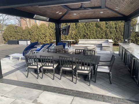 An outdoor patio space with a roof, ceiling fan, and in-ceiling speakers.