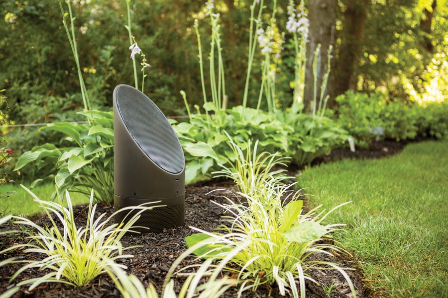 Coastal Source Bollard speaker in a green grassy area of a backyard