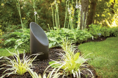 Coastal Source Bollard speaker in a green grassy area of a backyard