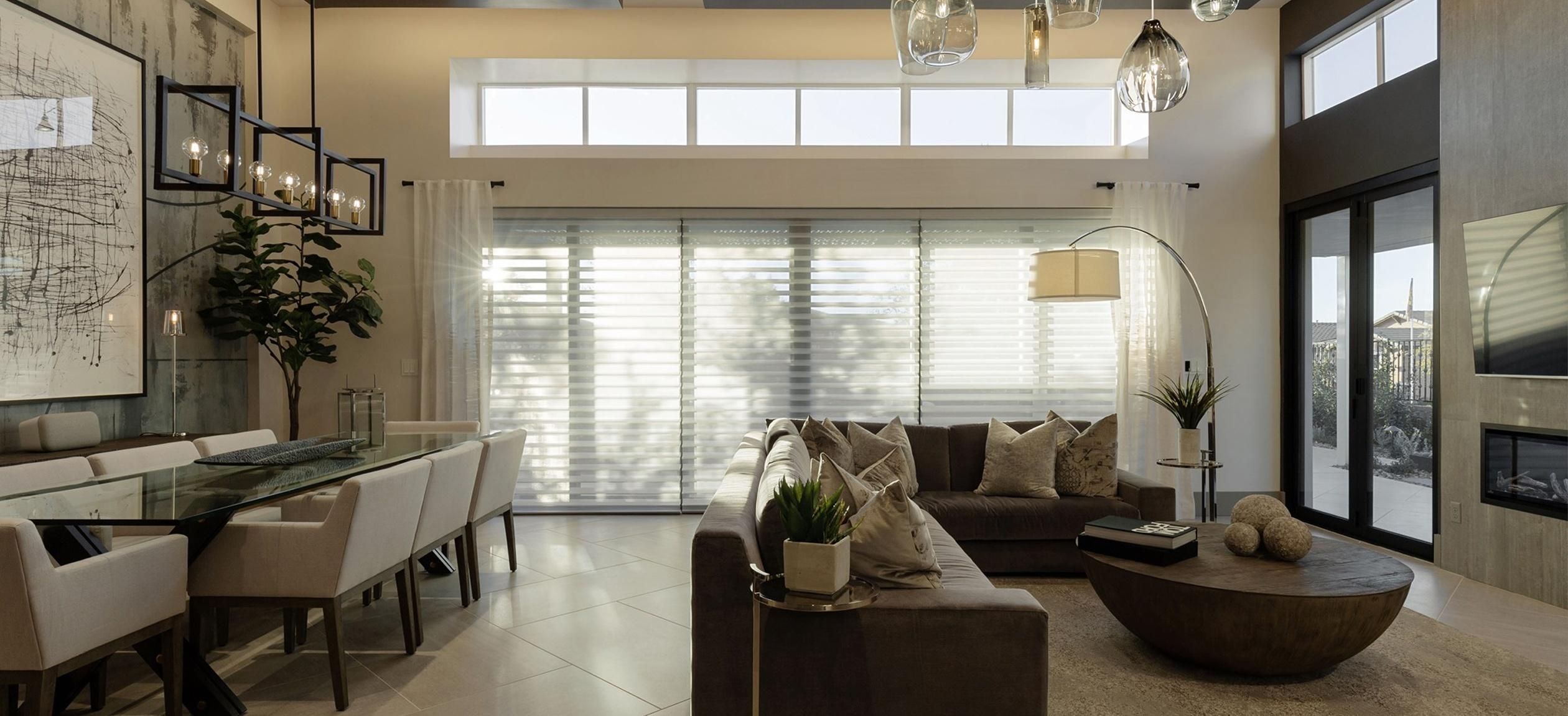 Modern living and dining area with large windows adorned with Hunter Douglas window treatments.