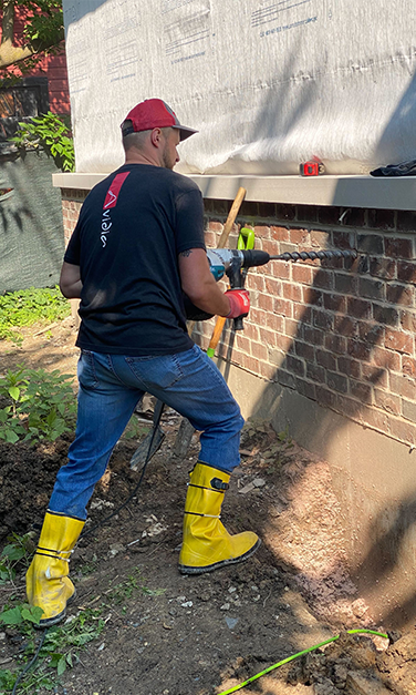Avidia service technician drilling into house wall for tech installation
